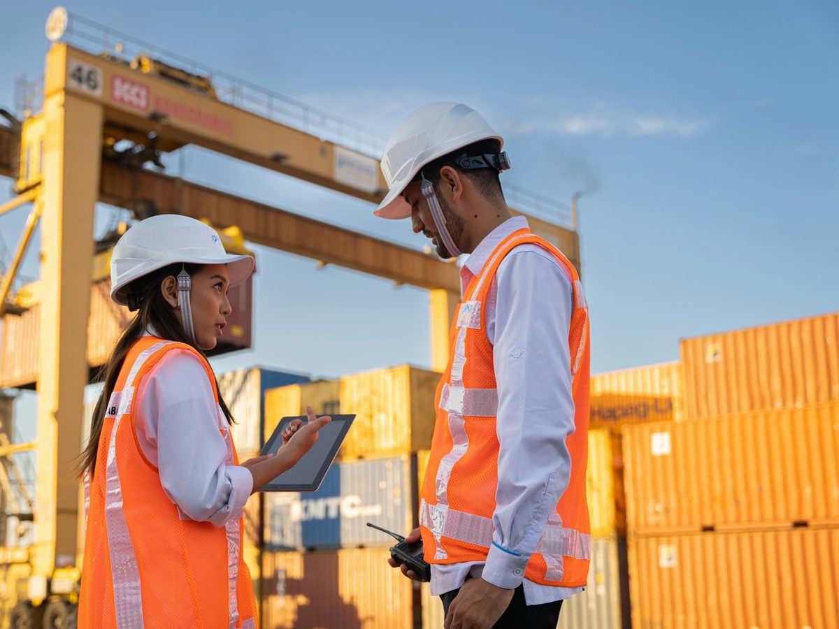 Noble Hepta logistics personnel in hard hats and safety vests coordinating cargo operations beside shipping containers