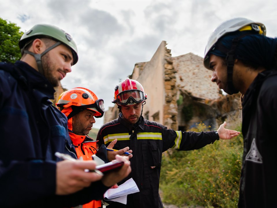 Engineers in helmets reviewing a laptop on site