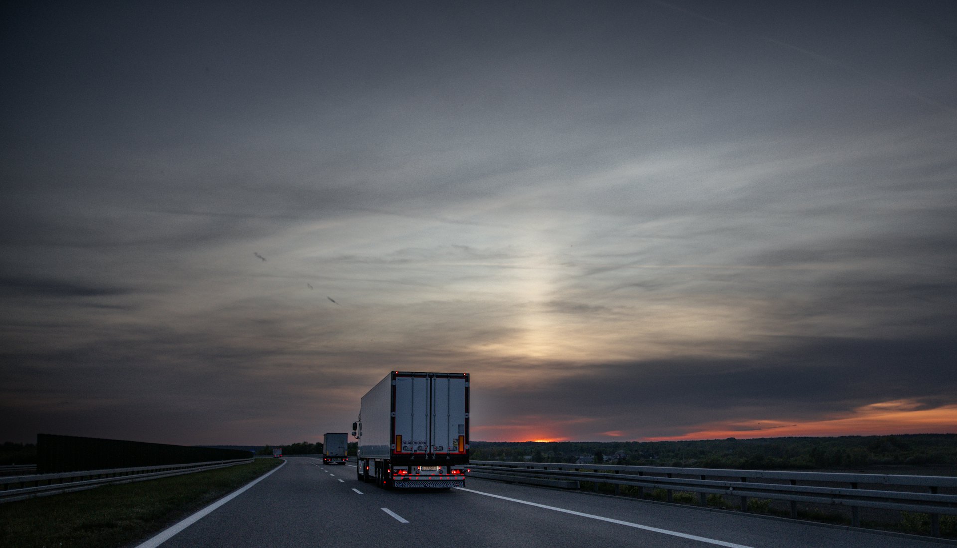 Freight trucks driving on a highway at sunset