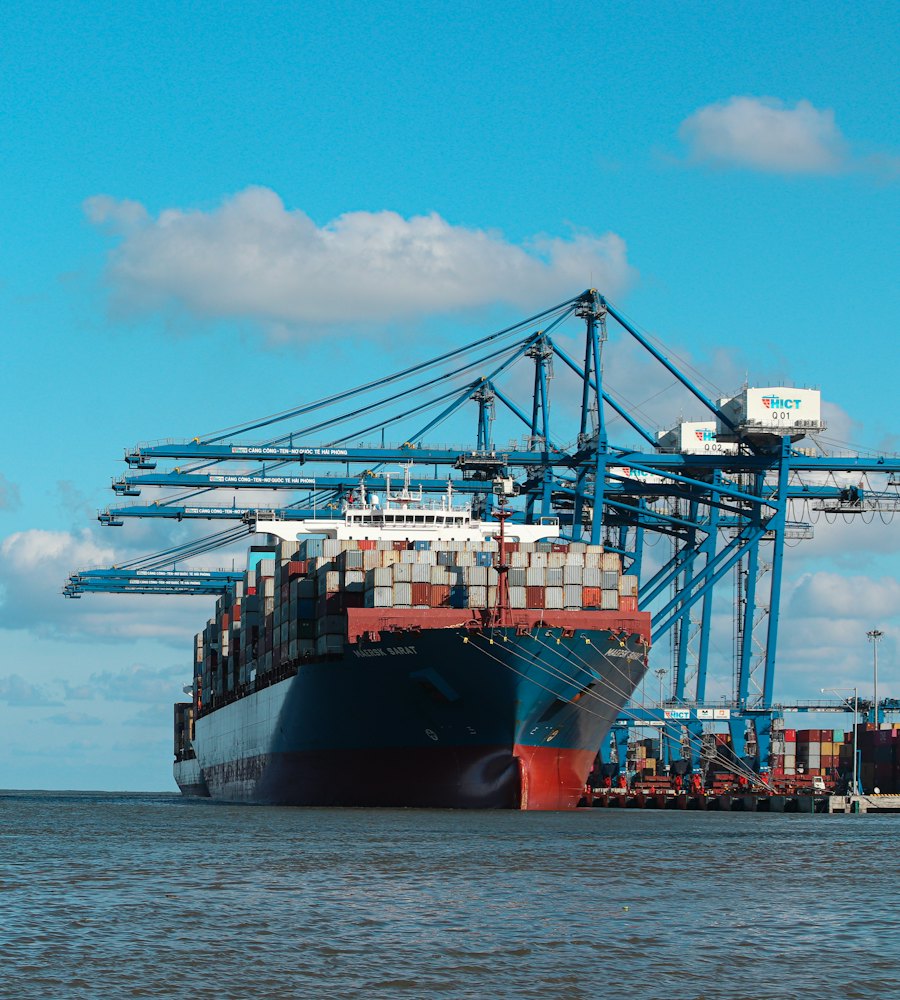Cargo ship docked under port cranes