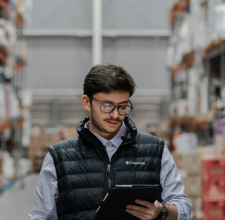 Warehouse supervisor in a vest holding a tablet