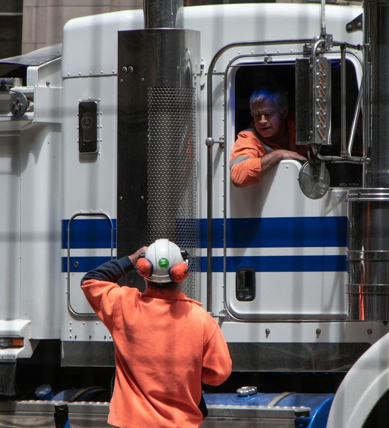 Driver in a high-visibility jacket beside a freight truck